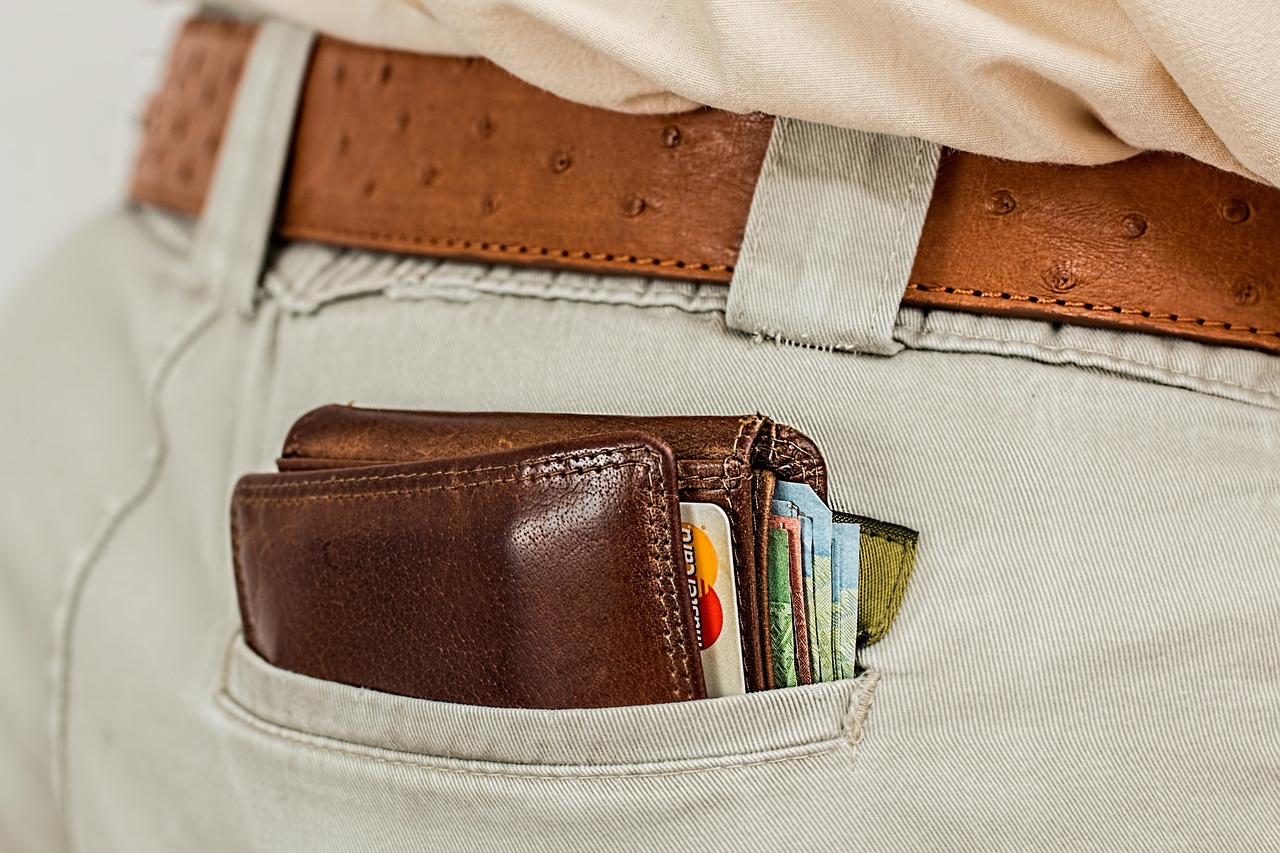 person holding hardware wallet next to laptop